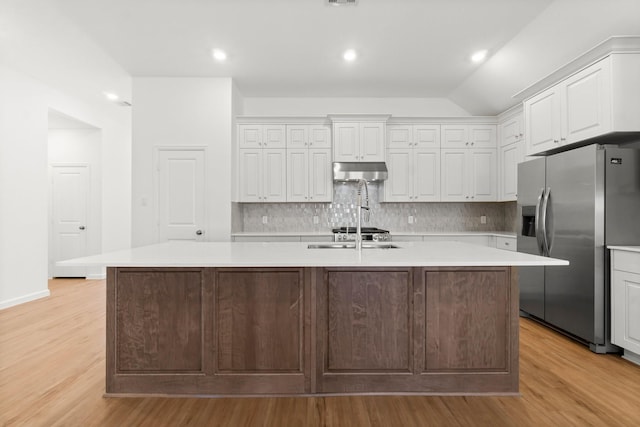 3315 Bristle Ridge Ln, Brookshire, TX 77423 - kitchen with stainless steel refrigerator with ice dispenser, under cabinet range hood, light wood-style floors, light countertops, and white cabinets