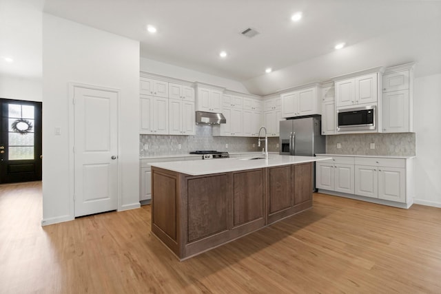 3315 Bristle Ridge Ln, Brookshire, TX 77423 - kitchen featuring appliances with stainless steel finishes, under cabinet range hood, light countertops, light wood-style flooring, and lofted ceiling