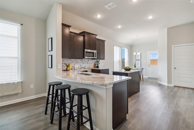 18414 Christine Elizabeth Ln, New Caney, TX 77357 - kitchen with stainless steel microwave, a sink, a center island, dark brown cabinetry, and dark wood-type flooring