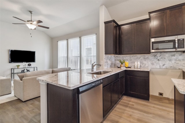 18414 Christine Elizabeth Ln, New Caney, TX 77357 - kitchen featuring stainless steel appliances, a sink, light stone counters, dark brown cabinets, and light wood-style flooring