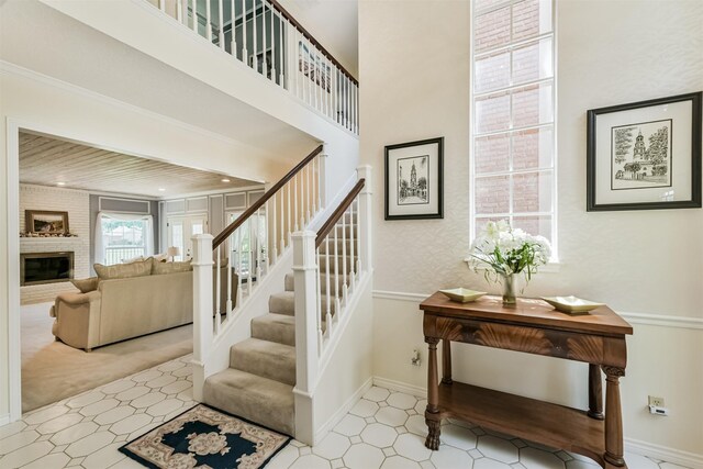 8410 Atascocita Lake Way, Humble, TX 77346 - staircase featuring a brick fireplace, tile patterned floors, baseboards, and a towering ceiling