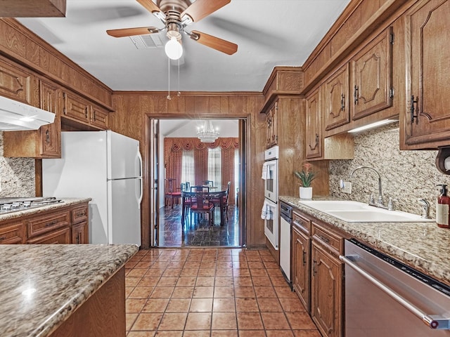 11821 15th St, Santa Fe, TX 77510 - kitchen with appliances with stainless steel finishes, a sink, decorative backsplash, a chandelier, and wooden walls