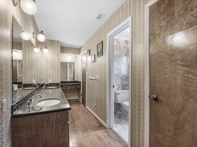 11821 15th St, Santa Fe, TX 77510 - bathroom featuring wood finished floors, toilet, wallpapered walls, and double vanity