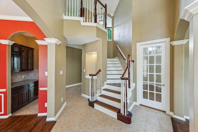 10707 Mandavilla Dr, Houston, TX 77095 - stairs with arched walkways, decorative columns, a high ceiling, baseboards, and tile patterned flooring