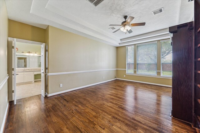 10707 Mandavilla Dr, Houston, TX 77095 - spare room featuring a tray ceiling, wood finished floors, a ceiling fan, a textured ceiling, and a sink