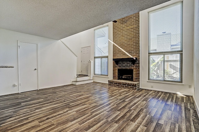 13948 Hollowgreen Dr Unit 25, Houston, TX 77082 - unfurnished living room featuring a textured ceiling, dark wood finished floors, and a brick fireplace