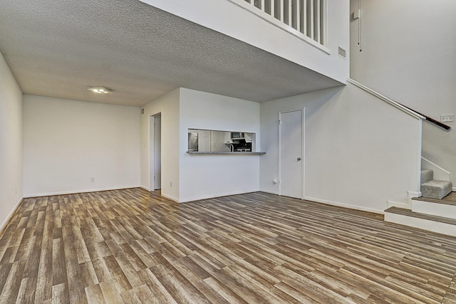 13948 Hollowgreen Dr Unit 25, Houston, TX 77082 - unfurnished living room with wood finished floors, stairway, a textured ceiling, and baseboards
