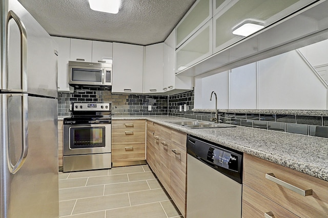 13948 Hollowgreen Dr Unit 25, Houston, TX 77082 - kitchen with stainless steel appliances, a sink, backsplash, a textured ceiling, and light tile patterned floors