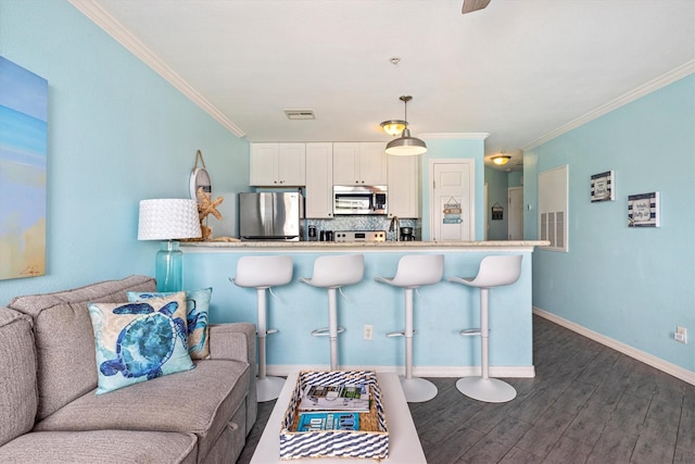 9520 Seawall Blvd Unit 152, Galveston, TX 77554 - kitchen featuring stainless steel appliances, a kitchen breakfast bar, dark wood-style flooring, ornamental molding, and decorative backsplash