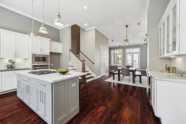 1032 W 18th St, Houston, TX 77008 - kitchen featuring appliances with stainless steel finishes, a kitchen breakfast bar, dark wood-style floors, white cabinetry, and tasteful backsplash
