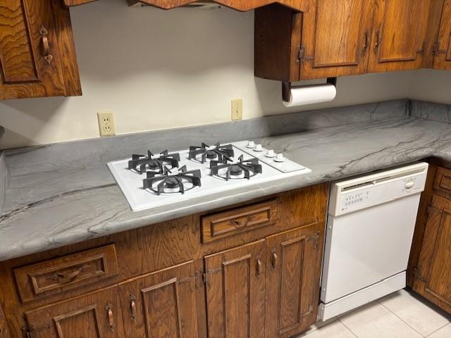 5542 Holly St Unit 206, Houston, TX 77081 - kitchen featuring white appliances, brown cabinetry, and light tile patterned flooring