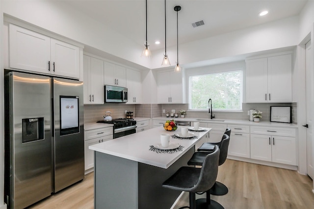 5703 Balbo St Unit B, Houston, TX 77091 - kitchen featuring stainless steel appliances, a sink, a breakfast bar area, light wood-style floors, and recessed lighting