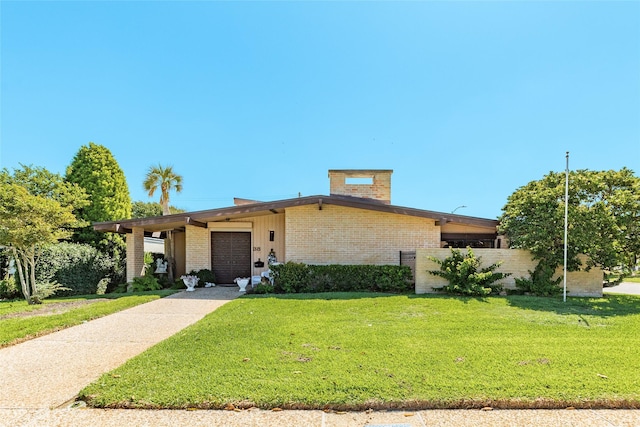 38 Adler Cir, Galveston, TX 77551 - mid-century modern home with a front lawn, an attached garage, and brick siding