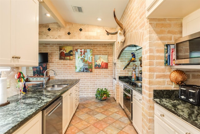 38 Adler Cir, Galveston, TX 77551 - kitchen with a sink, stainless steel appliances, brick wall, dark stone countertops, and light stone finish flooring