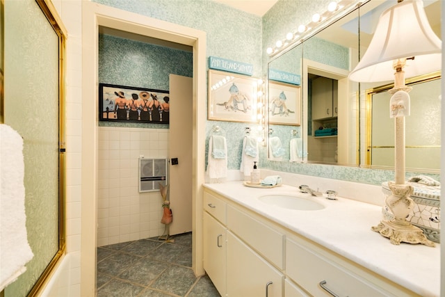 38 Adler Cir, Galveston, TX 77551 - full bathroom featuring a shower with door, tile patterned flooring, vanity, tile walls, and wallpapered walls