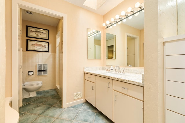 38 Adler Cir, Galveston, TX 77551 - bathroom featuring tile patterned flooring, toilet, tile walls, a skylight, and vanity