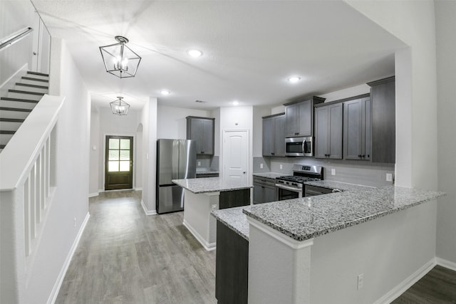 211 Rd 66111, Dayton, TX 77535 - kitchen with stainless steel appliances, a kitchen island, light stone counters, light wood-style flooring, and baseboards