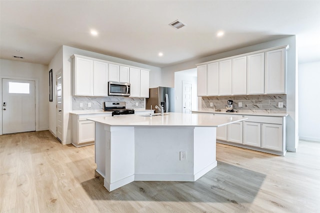 31611 Farlam Farms Trl, Fulshear, TX 77441 - kitchen featuring appliances with stainless steel finishes, a sink, light wood-style floors, an island with sink, and tasteful backsplash