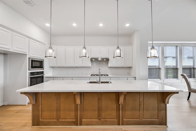 510 Rita Blanca Dr, Webster, TX 77598 - kitchen featuring oven, decorative backsplash, built in microwave, under cabinet range hood, and light wood-style floors