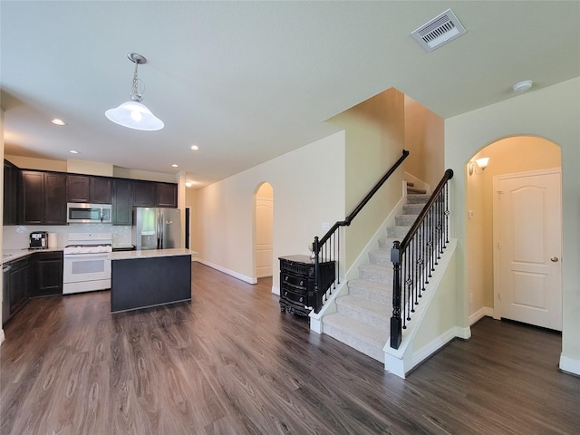 3430 Hughes Meadow Way, Richmond, TX 77406 - kitchen with appliances with stainless steel finishes, arched walkways, dark wood-style flooring, a kitchen island, and light countertops