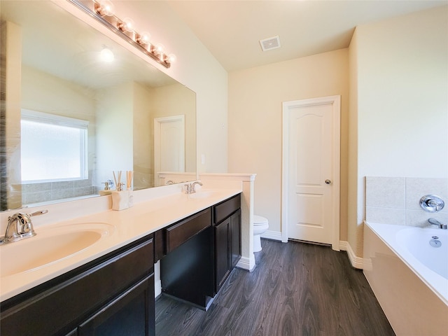 3430 Hughes Meadow Way, Richmond, TX 77406 - bathroom featuring toilet, a garden tub, wood finished floors, double vanity, and baseboards
