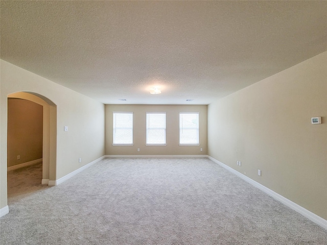 3430 Hughes Meadow Way, Richmond, TX 77406 - empty room with light colored carpet, arched walkways, a textured ceiling, and baseboards