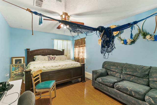 bedroom featuring wood finished floors, a textured ceiling, a ceiling fan, and baseboards