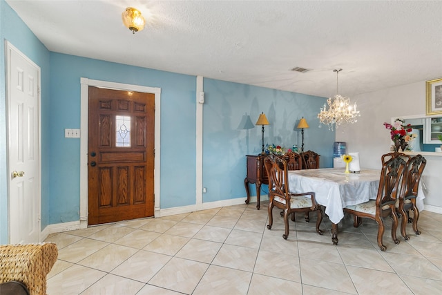 tiled dining space with a chandelier, baseboards, and a textured ceiling