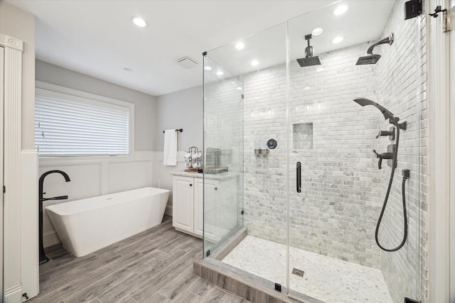 12310 Woodthorpe Ln, Houston, TX 77024 - bathroom featuring a shower stall, a soaking tub, wainscoting, recessed lighting, and wood finished floors