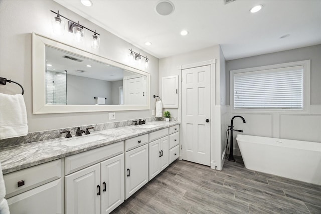 12310 Woodthorpe Ln, Houston, TX 77024 - full bath with double vanity, a freestanding tub, wood finished floors, and recessed lighting