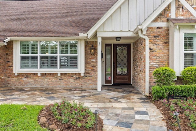 12310 Woodthorpe Ln, Houston, TX 77024 - entrance to property with board and batten siding, a shingled roof, and brick siding
