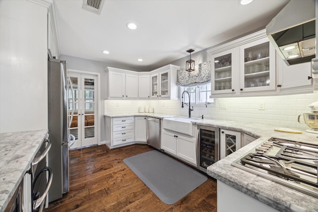 12310 Woodthorpe Ln, Houston, TX 77024 - kitchen with appliances with stainless steel finishes, range hood, french doors, light stone countertops, and white cabinetry