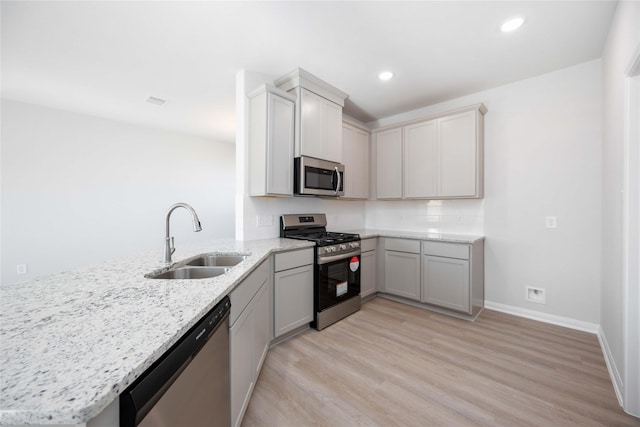 11765 Whirlaway Dr, Willis, TX 77318 - kitchen featuring appliances with stainless steel finishes, a sink, light stone countertops, light wood-style floors, and recessed lighting