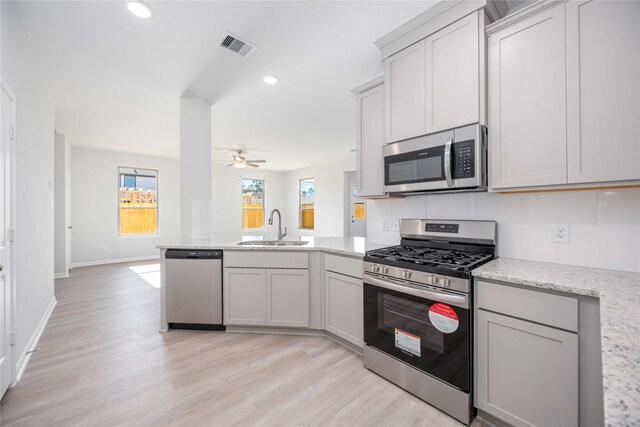 11765 Whirlaway Dr, Willis, TX 77318 - kitchen with appliances with stainless steel finishes, a sink, a peninsula, ceiling fan, and light wood-style flooring