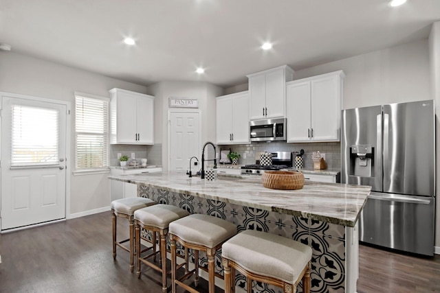 17723 Chartertree Ln, Tomball, TX 77377 - kitchen with stainless steel appliances, a sink, tasteful backsplash, a breakfast bar area, and dark wood-type flooring