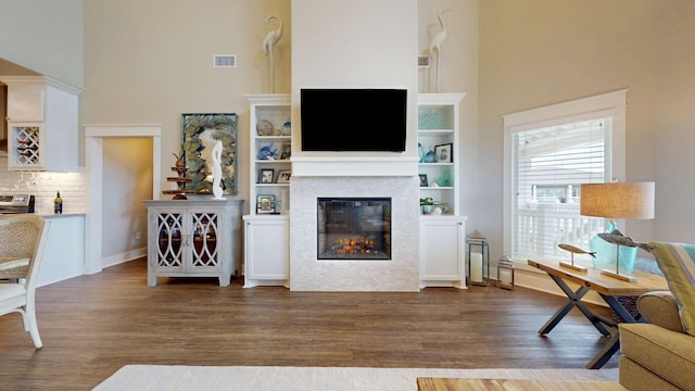 985 Sue Dr, Crystal Beach, TX 77650 - living room featuring a high ceiling, dark wood-style flooring, a glass covered fireplace, and baseboards
