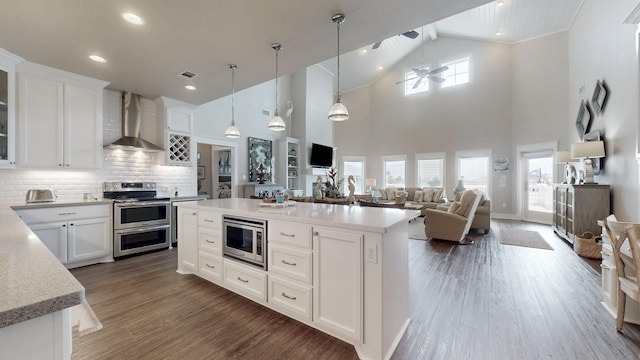 985 Sue Dr, Crystal Beach, TX 77650 - kitchen featuring wall chimney range hood, appliances with stainless steel finishes, a ceiling fan, white cabinets, and recessed lighting