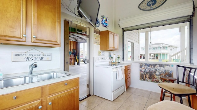 985 Sue Dr, Crystal Beach, TX 77650 - kitchen featuring white electric range, light countertops, a sink, light tile patterned floors, and brown cabinetry