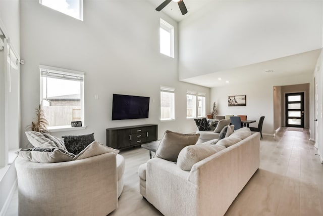 21606 Laggan Cliff Ln, Cypress, TX 77433 - living room with ceiling fan, a towering ceiling, baseboards, and light wood finished floors