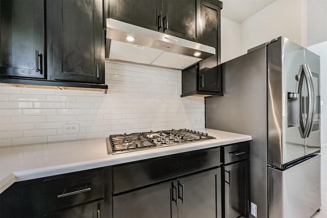 21606 Laggan Cliff Ln, Cypress, TX 77433 - kitchen featuring under cabinet range hood, stainless steel gas cooktop, light countertops, decorative backsplash, and dark cabinets
