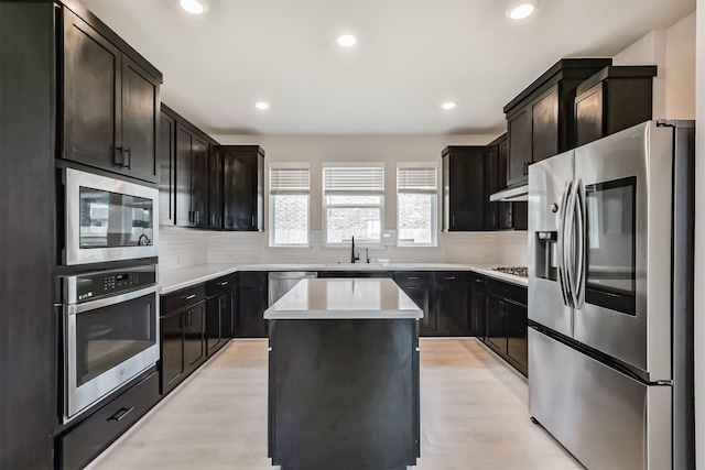 21606 Laggan Cliff Ln, Cypress, TX 77433 - kitchen featuring stainless steel appliances, under cabinet range hood, light wood-style flooring, a kitchen island, and recessed lighting