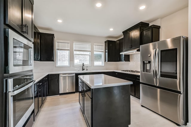 21606 Laggan Cliff Ln, Cypress, TX 77433 - kitchen with stainless steel appliances, dark cabinetry, under cabinet range hood, tasteful backsplash, and recessed lighting