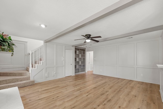 5310 Brownlee Ln, Spring, TX 77379 - unfurnished living room with a decorative wall, light wood finished floors, ceiling fan, stairs, and beamed ceiling