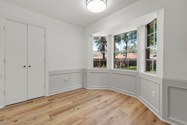 5310 Brownlee Ln, Spring, TX 77379 - unfurnished dining area featuring light wood finished floors, a wainscoted wall, a textured ceiling, and a decorative wall