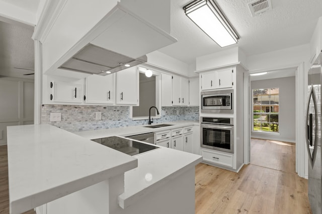 5310 Brownlee Ln, Spring, TX 77379 - kitchen featuring appliances with stainless steel finishes, a sink, a peninsula, island exhaust hood, and light wood finished floors