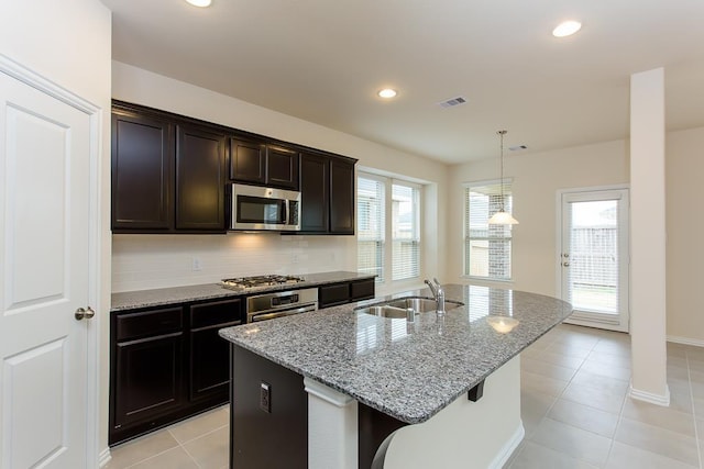 1626 Summer City Dr, Houston, TX 77047 - kitchen featuring appliances with stainless steel finishes, a kitchen island with sink, a sink, light stone counters, and light tile patterned floors