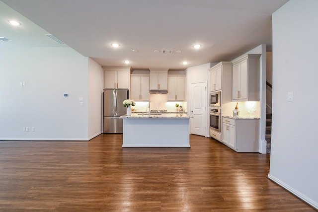 209 Cambria Green Ln, Katy, TX 77493 - kitchen with stainless steel appliances, dark wood finished floors, light stone countertops, a center island with sink, and recessed lighting
