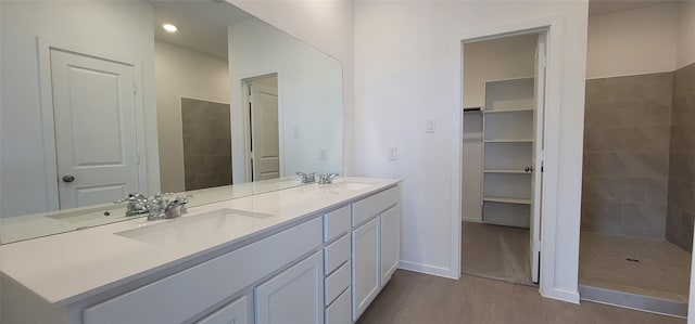 10619 Autumn Trace Dr, Beasley, TX 77417 - full bathroom featuring wood finished floors, double vanity, baseboards, a spacious closet, and tiled shower