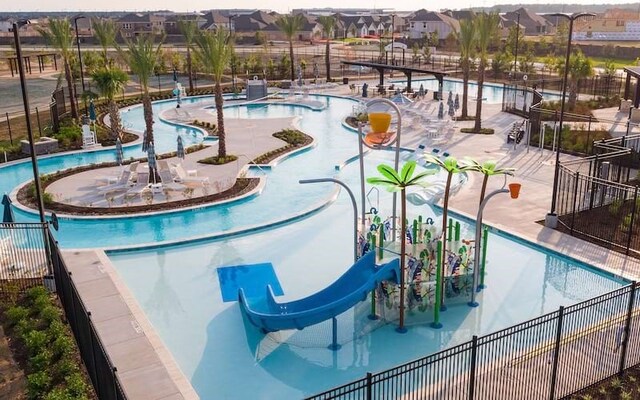 7911 Palm Sails Ln, Cypress, TX 77433 - community pool featuring a water slide, fence, a residential view, and a water play area
