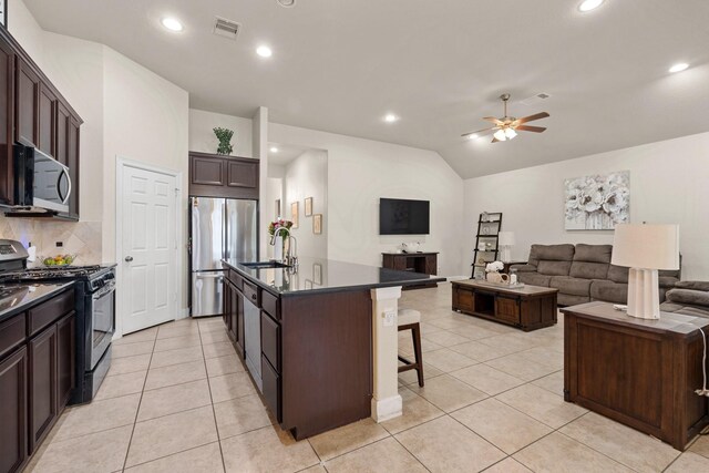 17222 Fable Springs Ln, Cypress, TX 77433 - kitchen featuring appliances with stainless steel finishes, dark countertops, a ceiling fan, a kitchen bar, and a sink